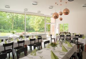 a dining room with white tables and chairs and large windows at Hotel Christophorus in Berlin