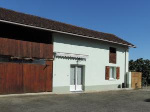 une maison blanche avec un garage marron et blanc dans l'établissement Gite au calme en Armagnac, à Sion