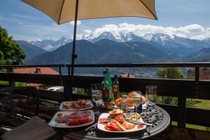 a table with plates of food on a balcony with mountains at Mont Blanc Views Apartments in Passy