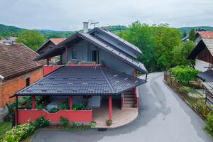 a house with a black roof on a street at Apartment Kolaković in Slunj