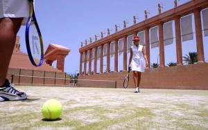 a woman in a white dress holding a tennis racket at Hotel Cleopatra Palace in Playa de las Americas