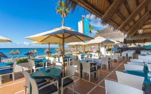 a restaurant with chairs and tables and umbrellas on the beach at Hotel Cleopatra Palace in Playa de las Americas
