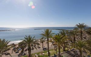 a view of a beach with palm trees and the ocean at Hotel Cleopatra Palace in Playa de las Americas