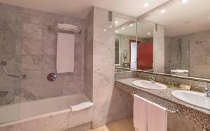 a bathroom with two sinks and a tub and a shower at Hotel Cleopatra Palace in Playa de las Americas