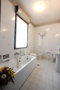 a bathroom with a tub and a toilet and a window at Hotel Excelsior in Latina