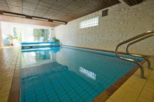 ein Swimmingpool mit blauen Fliesen in einem Gebäude in der Unterkunft Mein Vierjahreszeiten Hotel Garni Superior in Sankt Andreasberg