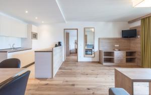 eine Küche und ein Esszimmer mit weißen Wänden und Holzböden in der Unterkunft Aparthotel Panorama in Gais