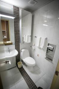 a bathroom with a toilet, sink, and mirror at Hotel Hu Incheon Airport in Incheon