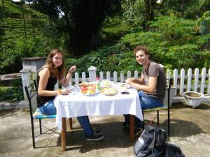 a man and woman sitting at a table eating food at Niwasa House in Hatton