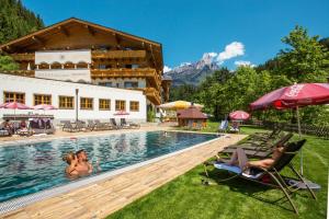grupa ludzi siedząca na krzesłach przy basenie w obiekcie Landhotel Alpenhof Filzmoos w mieście Filzmoos