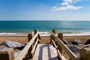 ein Holztor am Strand mit dem Meer in der Unterkunft The Cricket Inn in Beesands