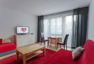 ライプツィヒにあるApartments Zentrum Brühlのリビングルーム(赤いソファ、テーブル付)