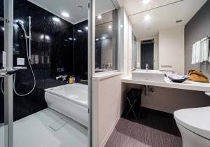 a bathroom with a tub and a toilet and a sink at Daiwa Roynet Hotel Koriyama Ekimae in Koriyama