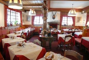 a restaurant with tables and chairs with red and white table cloth at Affittacamere Lou Ressignon in Cogne