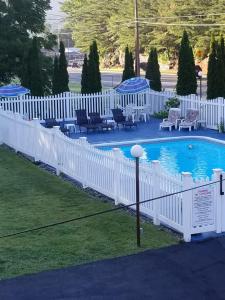 a white fence next to a swimming pool with chairs at Seven Dwarfs Motel & Cabins in Lake George