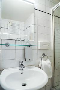 W białej łazience znajduje się umywalka i lustro. w obiekcie Hotel Niederräder Hof w Frankfurcie nad Menem