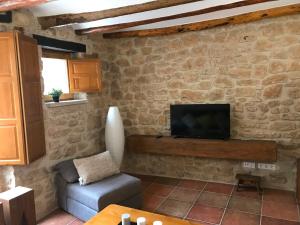 a living room with a tv on a stone wall at Cal Triquell in El Vilosell