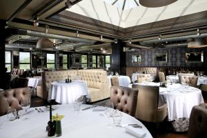 un restaurant avec tables et chaises et nappes blanches dans l'établissement Cameron House on Loch Lomond, à Balloch