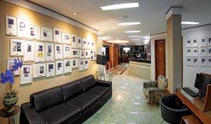 Lira Hotel في كوريتيبا: غرفة معيشة مع أريكة وصور على الحائط