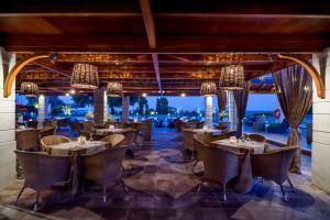 a restaurant with tables and chairs and a view of the ocean at Dion Palace Resort and Spa in Limín Litochórou