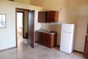 una cucina con frigorifero bianco e armadietti in legno di Agriturismo L'Assiolo a Miglionico