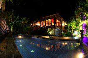 a swimming pool in front of a house at night at Villa Gede Private Guest House in Selemadeg