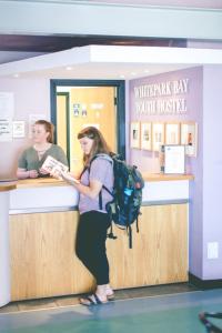 White Park Bay Youth Hostel في بالينتوي: امرأة تقف في كونتر في شعاع الحياة البرية يستحق الفندق