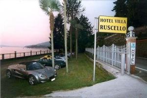 two cars parked next to a hotel with a sign at Hotel Villa Ruscello in Baveno