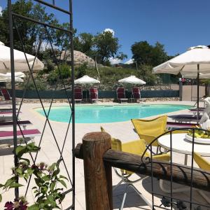 een zwembad met stoelen, tafels en parasols bij Residence Garden in Tignale