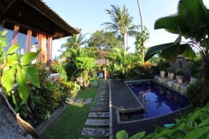 a garden with a swimming pool in front of a house at Villa Gede Private Guest House in Selemadeg