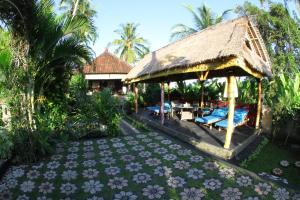 an outdoor pavilion with chairs and a thatched roof at Villa Gede Private Guest House in Selemadeg