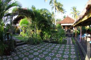 a garden with flowers and palm trees and a building at Villa Gede Private Guest House in Selemadeg