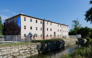 a large white building next to a river at ibis budget Orange Centre in Orange