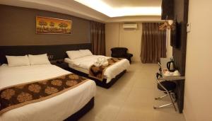 ein Hotelzimmer mit 2 Betten und einem Stuhl in der Unterkunft Golden Leaves Hotel in Malakka