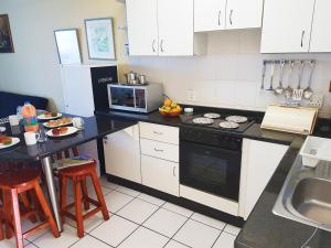 cocina con armarios blancos y encimera negra en Dumela Margate Flat No 22, en Margate