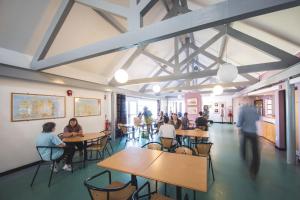a group of people sitting at tables in a cafeteria at White Park Bay Youth Hostel in Ballintoy