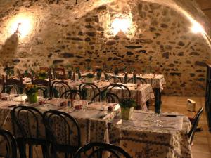 comedor con mesas y sillas y pared de piedra en Auberge Roman, en La Javie