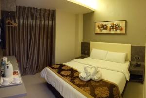Una habitación de hotel con una cama con dos cisnes. en Golden Leaves Hotel, en Melaka