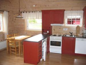 a kitchen with red cabinets and a white stove top oven at Røldal Hyttegrend & Camping in Røldal