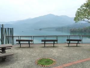 three benches sitting next to a view of a lake at Sun Fog Hotel in Yuchi