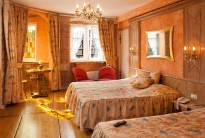 a hotel room with two beds and a chandelier at Hotel Saint-Martin in Colmar