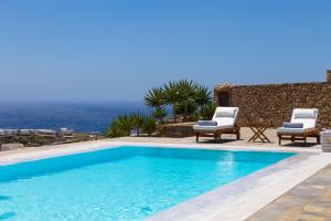 a swimming pool with two chairs and a view of the ocean at Elia Sea View Luxury Villa in Elia Beach