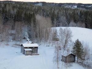 zwei Gebäude auf einem schneebedeckten Feld mit Bäumen in der Unterkunft Marjas stuga in Norråker