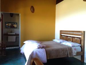 1 dormitorio con cama y pared amarilla en Pousada Encantos do Cerrado, en Delfinópolis