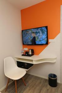 a room with a white chair and a tv on a wall at M&M Hotel in Kuala Lumpur