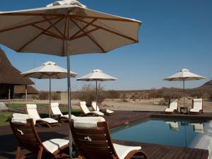 a group of chairs and umbrellas next to a pool at Tutwa Desert Lodge in Augrabies