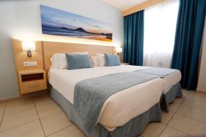 a hotel room with a large bed with blue curtains at Hotel-Apartamentos Andorra in Playa de las Americas