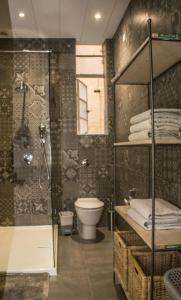 a bathroom with a toilet and a glass shower at Vincenti Strait Street Suite in Valletta