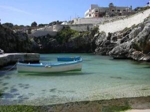a boat sitting in the water next to a cliff at La Casetta in Poggiardo