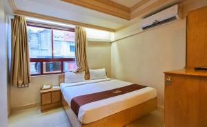 Habitación pequeña con cama y ventana en Hotel Swan Inn, en Pune